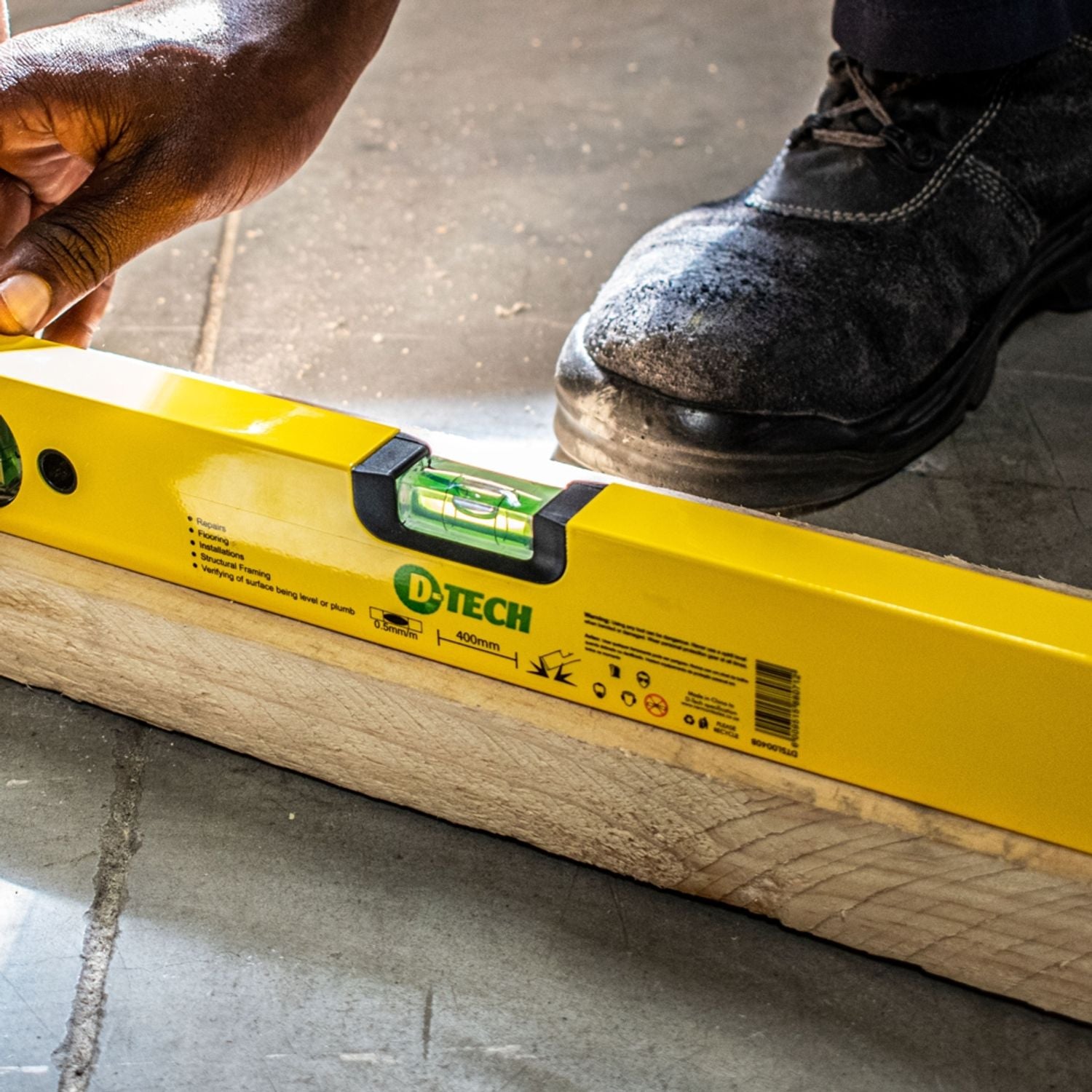 Yellow spirit level resting on wood, green vial visible