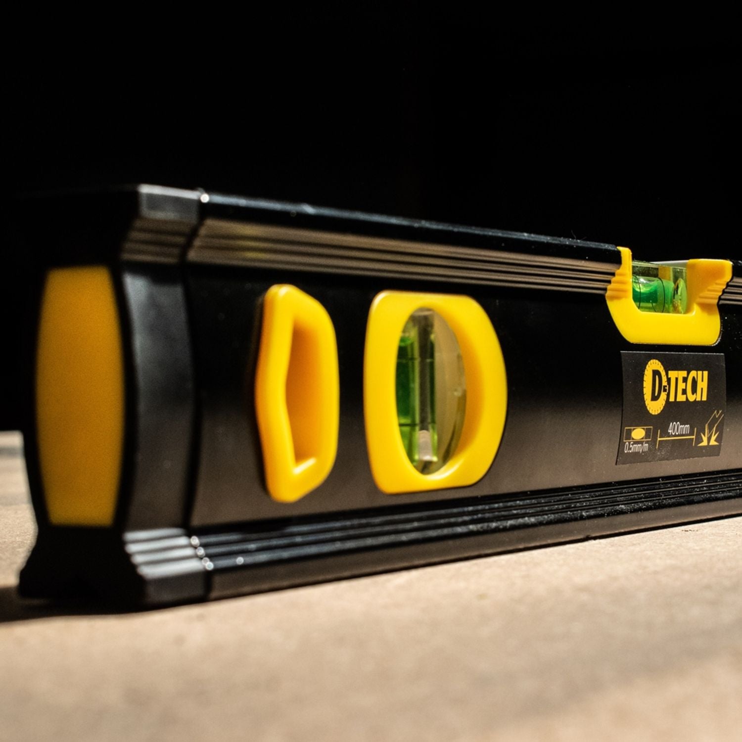 Spirit level close-up with yellow vials and D-Tech branding on black casing