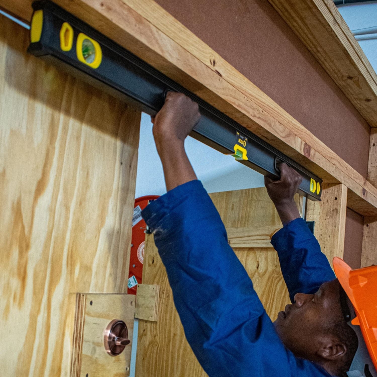 Spirit level resting on ceiling joists during construction, black and yellow body