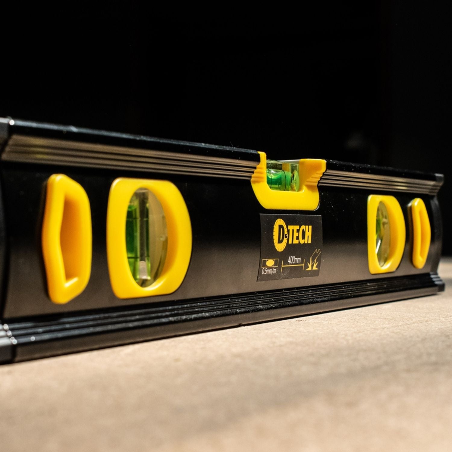 Black spirit level close-up with yellow vials and measurement markings